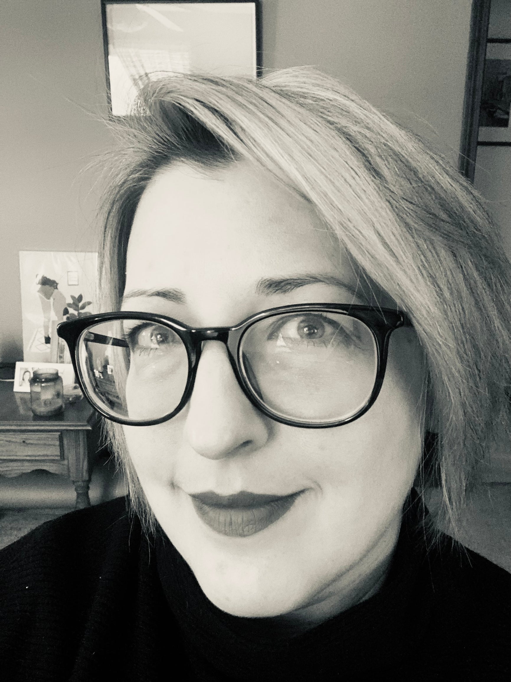 Headshot of Trisha who is a white woman with short blonde hair and large black glasses. 